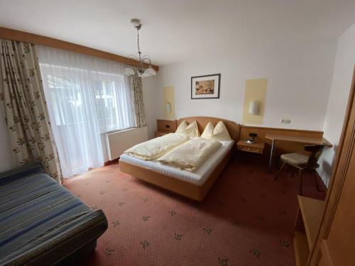 a bedroom with a bed and a desk and a window at Harpfner in Finkenberg