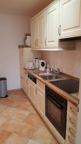 a kitchen with white cabinets and a sink at Feriengarten Dahme W 9 in Dahme