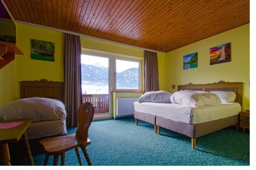 a bedroom with two beds and a table and a window at Hotel Sonnleitn in Jenig