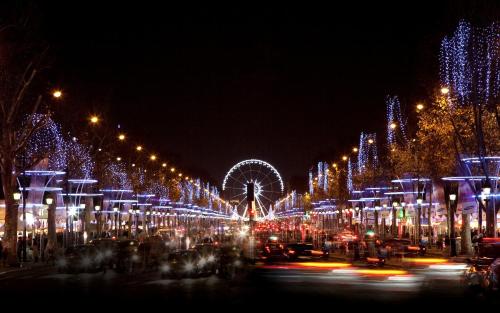 a lit up city at night with a ferris wheel at La Tremoille Paris in Paris