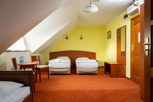 a bedroom with two beds and a table and chairs at Hotel Bastion in Kostrzyn nad Odrą