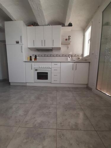 a kitchen with white cabinets and a tile floor at Can Blau in Roses