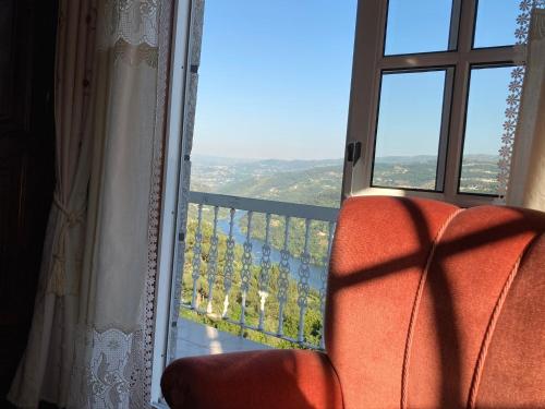 an orange chair sitting in front of a window at Mira Douro Valley Home in Marco de Canaveses