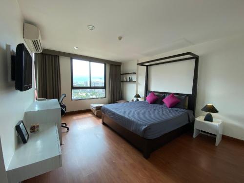 a bedroom with a large bed with pink pillows at Teddy@Thammasart in Pathum Thani