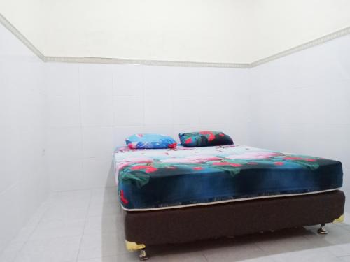 een bed in een witte kamer met twee kussens erop bij D'Kost Ketintang in Surabaya