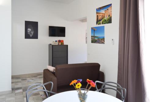 ein Wohnzimmer mit einem Tisch, einem Stuhl und einem Sofa in der Unterkunft Quattroquarti Stradivari Home in Noto