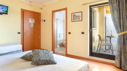 a bedroom with a bed and a door to a bathroom at Hotel Postumia in Dossobuono