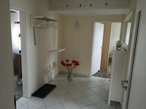 a hallway with a vase with red flowers in it at Ferienwohnung - Nadine in Georgsmarienhütte