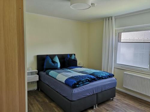 a bedroom with a bed with blue pillows and a window at Ferienwohnung - Nadine in Georgsmarienhütte