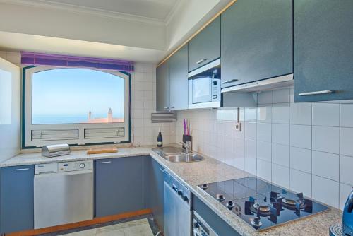 a kitchen with a sink and a window at Sea Front Family Apartment in Parede