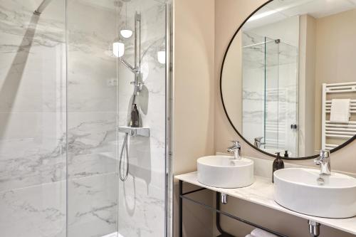 a bathroom with two sinks and a shower at Aparthotel & Spa Adagio Vannes in Vannes