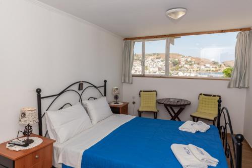 1 dormitorio con 1 cama, 2 sillas y ventana en El Greco Studios, en Patmos