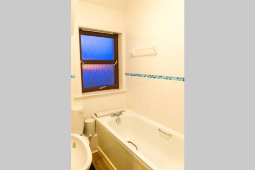 a bathroom with a tub and a toilet and a window at Modern Spacious Central Apartment in Portree