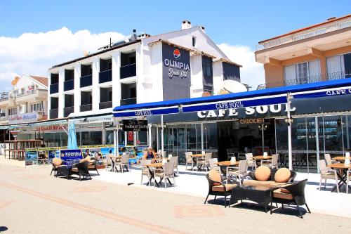 a cafe outpost with tables and chairs in front of a building at Olimpia Hotel in Fethiye