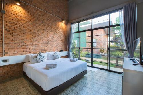 The Forest for rest resort Khao Yai في Ban Tha Maprang: غرفة نوم بسرير كبير وجدار من الطوب