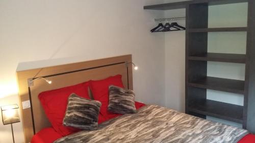 1 dormitorio con 1 cama roja y 2 almohadas en T2 cabine vue montagne Valnéa Peyragudes en Germ