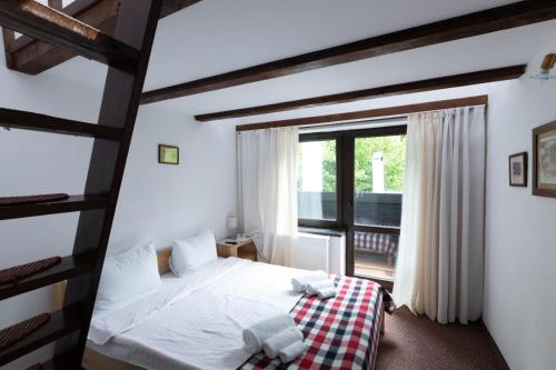 ein Schlafzimmer mit einem Bett und einem großen Fenster in der Unterkunft Club Rossignol in Poiana Brașov