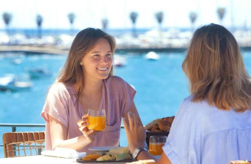 two women sitting at a table with a glass of orange juice at Villa Cascais Boutique Hotel in Cascais