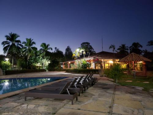 a pool with lounge chairs and a house at night at Pousada Recanto dos Passaros in Balsas