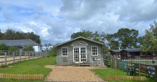 a small shed in a field next to a fence at Owls Nest Log Cabin in Morpeth