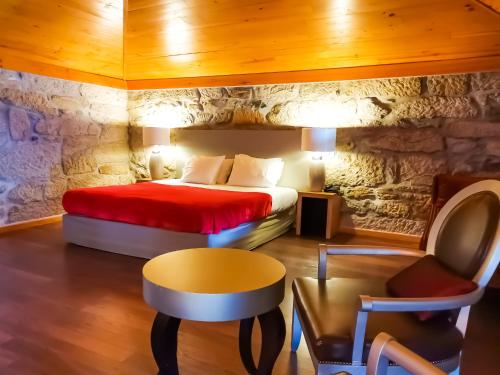 1 dormitorio con 1 cama con pared de piedra en Casas Novas Countryside Hotel Spa & Events en Chaves