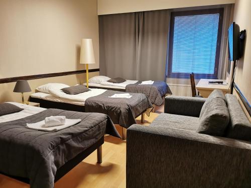 a hotel room with four beds and a couch at Sport Hotel Kantri in Kankaanpää