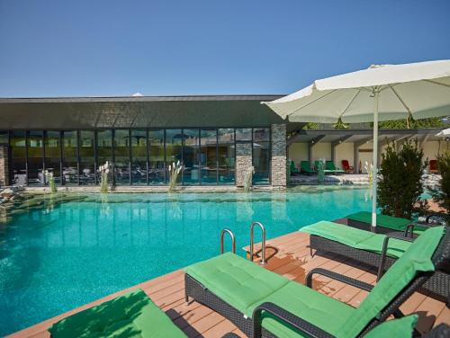 a swimming pool with two chairs and an umbrella at Hotel Heselbacher Hof in Baiersbronn