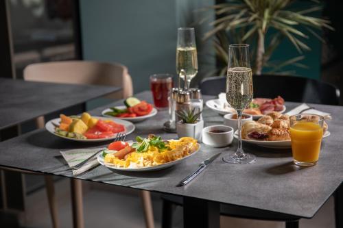 a table with plates of food and glasses of orange juice at Cortile Hotel - Adults Only in Budapest