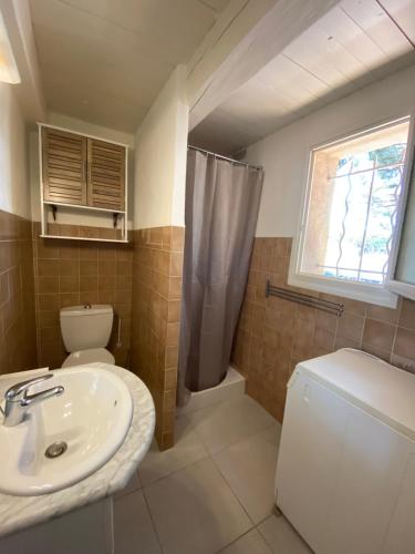 een badkamer met een wastafel en een toilet en een raam bij Appartement Les grands pins in Les Issambres