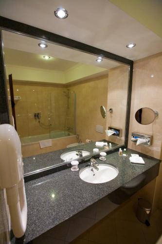 a bathroom with two sinks and a large mirror at Ramada Hotel & Suites by Wyndham Bucharest North in Bucharest