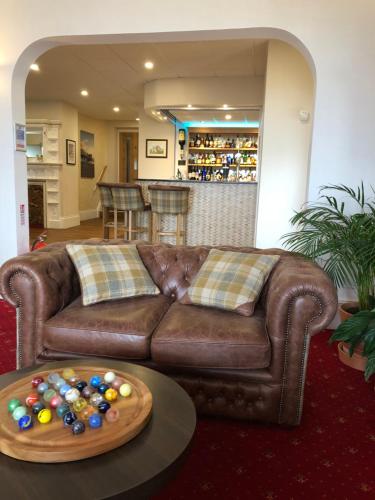 a living room with a brown couch and a table with balls at Queenswood Hotel in Weston-super-Mare