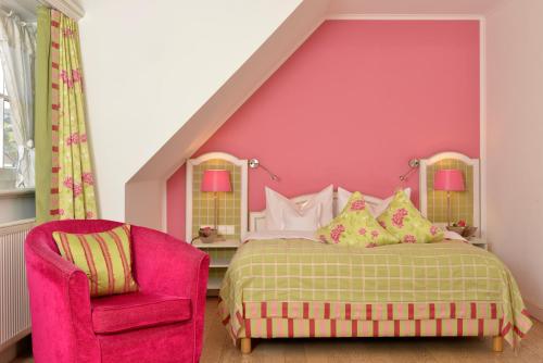 a pink bedroom with a bed and a pink chair at Romantik Hotel & Restaurant Hirsch in Sonnenbühl