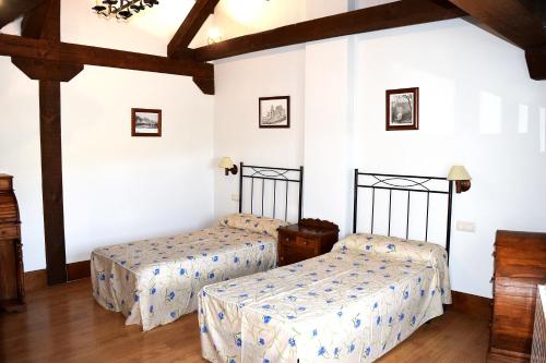 Duas camas num quarto com paredes brancas e pisos em madeira em La Canaleja em Torre Val de San Pedro