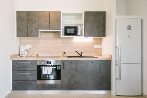 a kitchen with gray cabinets and a white refrigerator at Apartman Balaton in Keszthely
