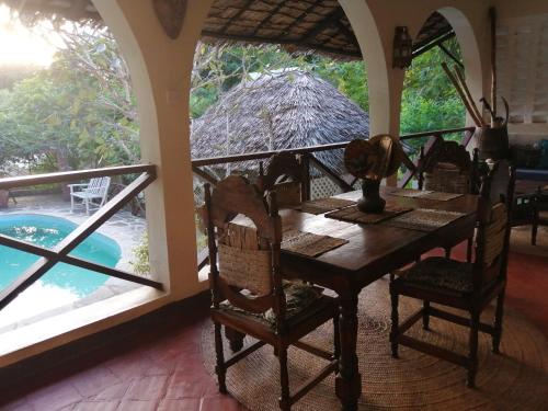 a dining room with a table and a view of a pool at Sunset villas Tropical Garden House in Kilifi