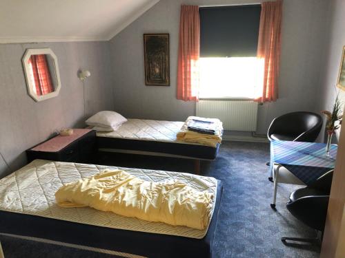a room with two beds and a chair and a window at Älvtomt in Krylbo