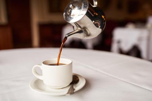 a person pouring coffee into a cup on a table at The Orwell Hotel in Felixstowe