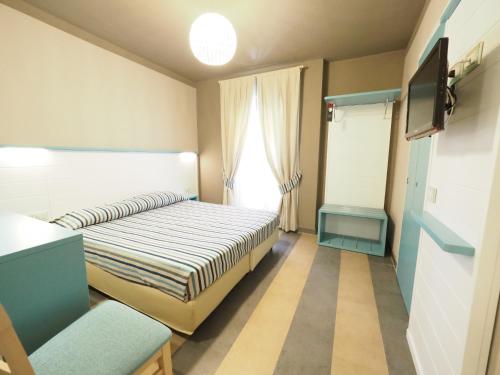 Habitación pequeña con cama y TV. en Hotel La Spiaggia en Monterosso al Mare