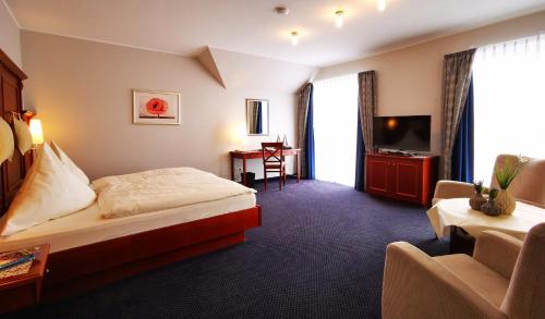 Habitación de hotel con cama y TV en Hotel Garni Bendiks, en Horumersiel