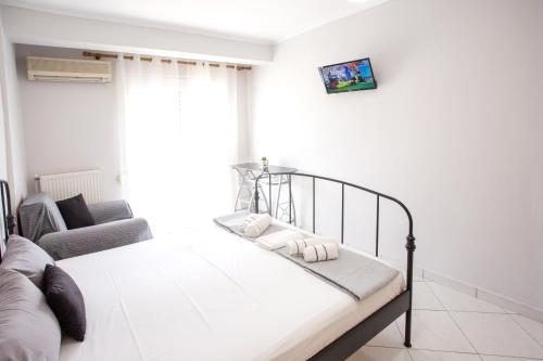 a white bedroom with a bed and a couch at Ammos Studios & Apartments in Nea Peramos