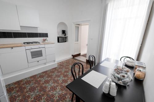 une cuisine avec une table noire, des chaises et une cuisinière dans l'établissement Pegaso, à Catane