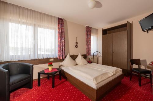 um quarto de hotel com uma cama e uma cadeira em Hotel Restaurant Häsfeld em Überherrn