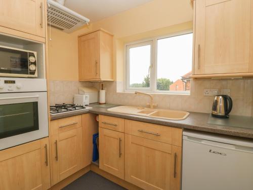 a kitchen with wooden cabinets and a sink and a window at The Gables in York