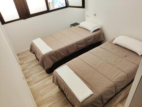 two beds in a small room with windows at Palafox 23 in Madrid