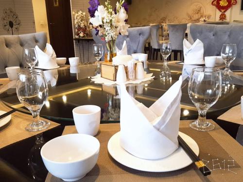 Jade Dragon Hotel DHA Lahore في لاهور: طاولة غرفة الطعام مع الأطباق البيضاء وكؤوس النبيذ