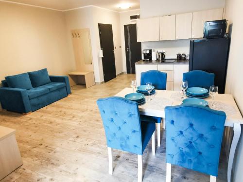 uma cozinha e sala de jantar com uma mesa e cadeiras azuis em Apartament Dominikana em Sianozety