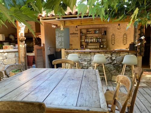 une table et des chaises en bois devant un bar dans l'établissement Hotel gite d'etape San Pasquale, à Conca
