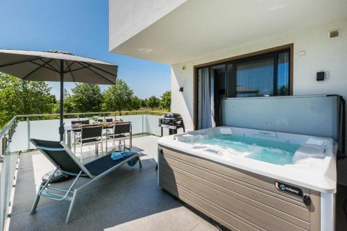 einen Whirlpool auf einem Balkon mit einem Stuhl und einem Sonnenschirm in der Unterkunft Luxus SPA Fewo MARITIME DREAM WE 3 in Göhren-Lebbin