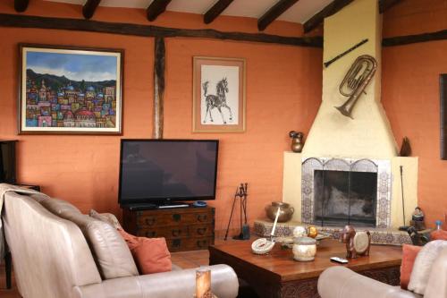 uma sala de estar com televisão e lareira em Hacienda El Rejo em Machachi