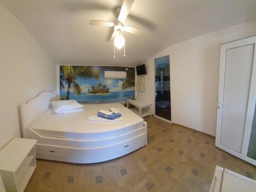 een slaapkamer met een groot wit bed en een plafondventilator bij Casa Carmen in 2 Mai